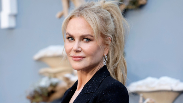 Nicole Kidman poses at an event in a black jacket. She wears her hair in a ponytail.